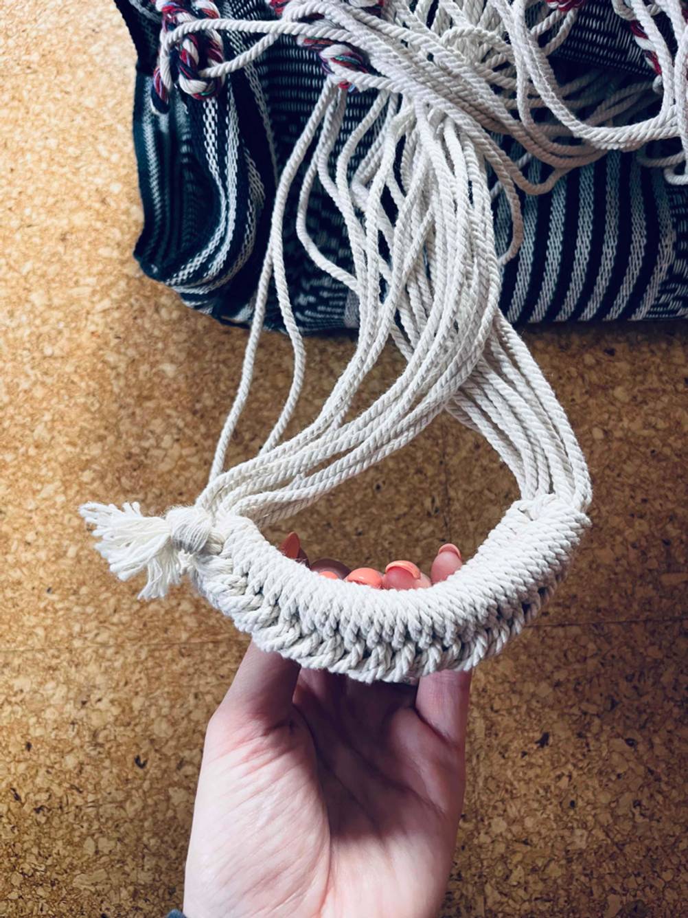 Hand hält verstärkten Hänge-Gurt einer gemusterten Outdoor-Hängematte im Test.