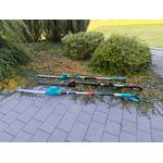 Drei Teleskop-Heckenscheren liegen nebeneinander auf gepflasterten Steinen.