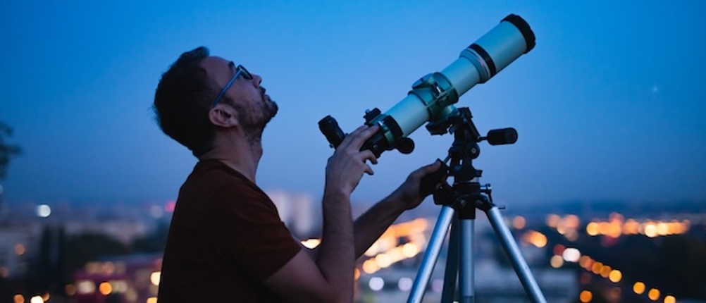 Teleskop im Test: Ein Mann betrachtet mit einem weißen Teleskop den Abendhimmel.