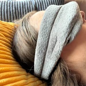 Eine Person liegt mit der Tempur-Schlafmaske auf einem Kissen.