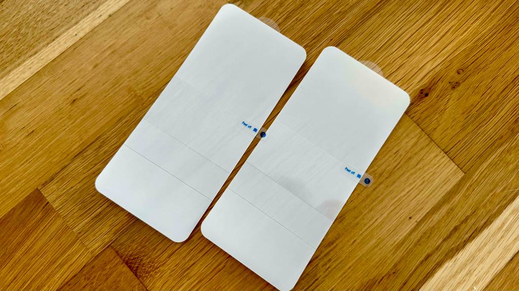 Zwei getestete Samsung-Galaxy-S20-FE-Panzergläser liegen auf einer Holzoberfläche.