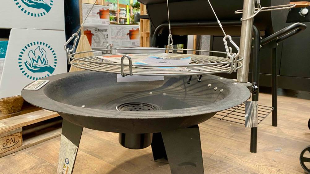 Im Test: Ein Schwenkgrill von der Seite mit angehobenem Rost.