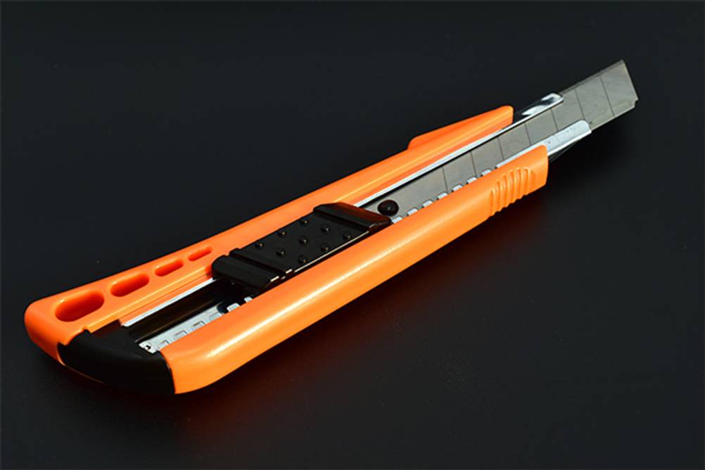 Teppichmesser im Test: Ein orangenes Teppichmesser vor einem schwarzen Hintergrund.