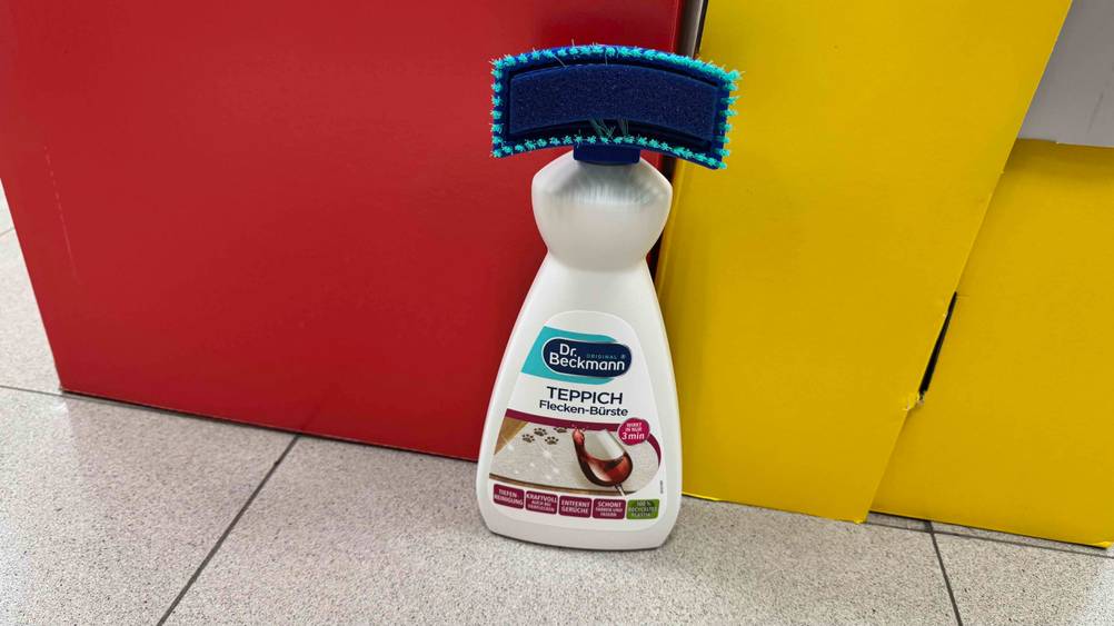 Das getestete Teppichshampoo vor Kartons auf dem Boden stehend.