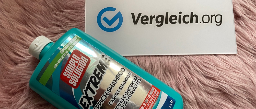 Simple-Solution-Teppichshampoo neben einem Schild von Vergleich.org liegend auf einem Fell