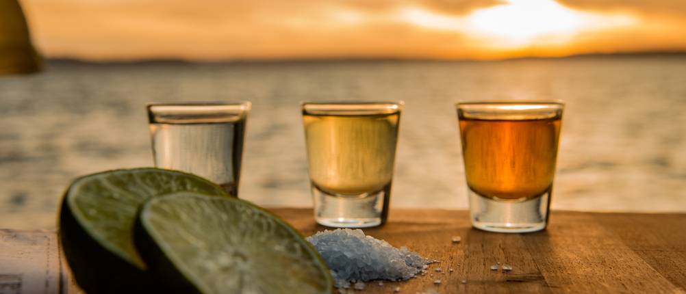 Tequila im Test: Drei Tequila-Shots auf einem Tisch vor dem Meer. 