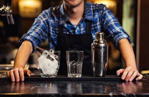 Tequila im Test: Ein Barkeeper mit Glas, Eis und Shaker.