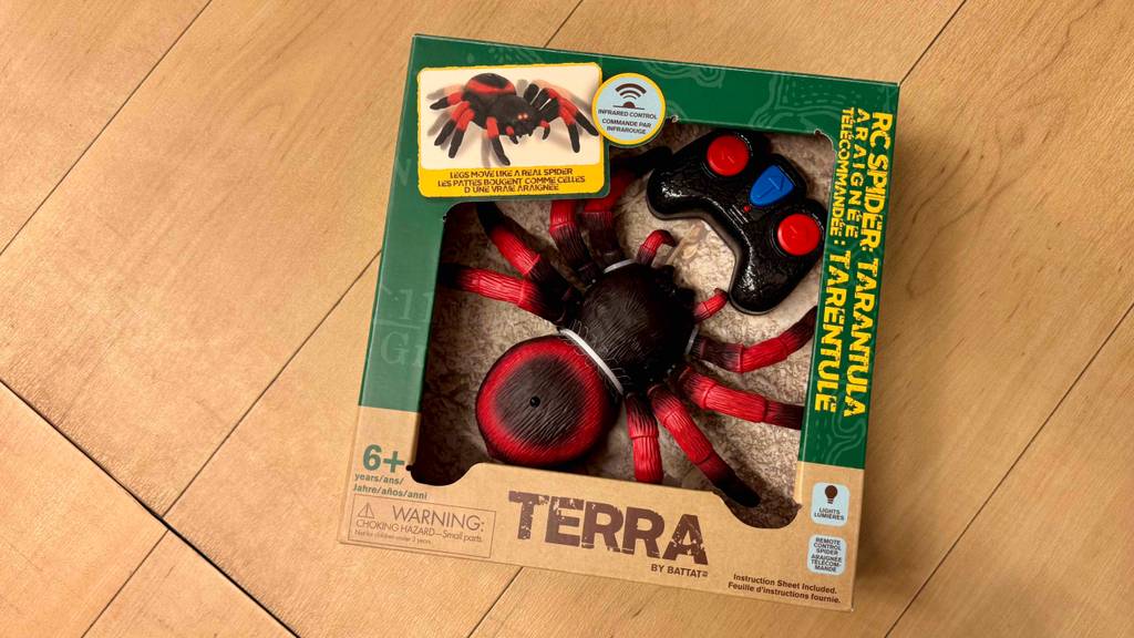 Die ferngesteuerte Spinne im Test befindet sich in der Verpackung auf einem Holzfußboden.