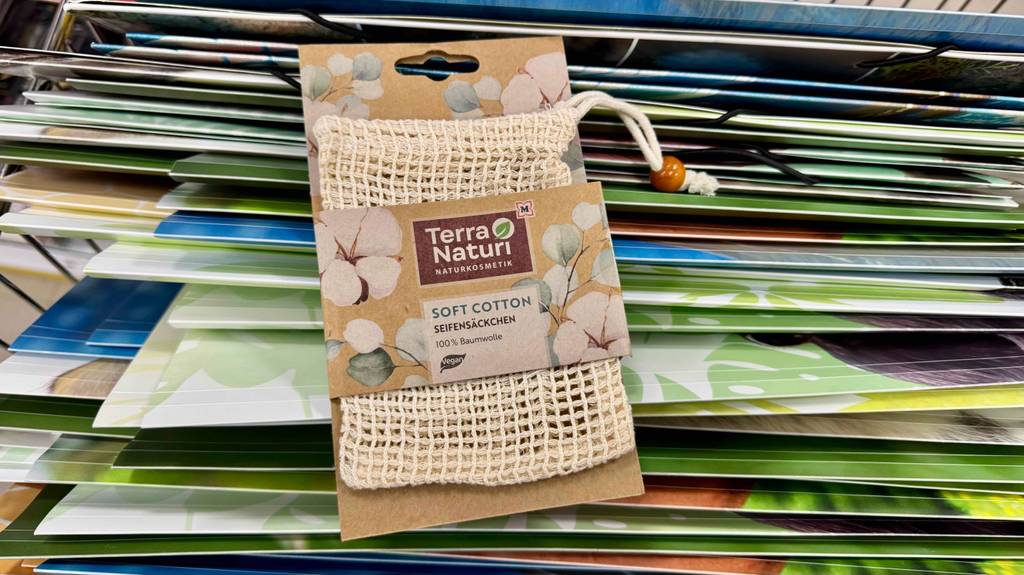 Ein verpacktes Seifensäckchen steht zum testen vor zusammengelegten Pappkartons.