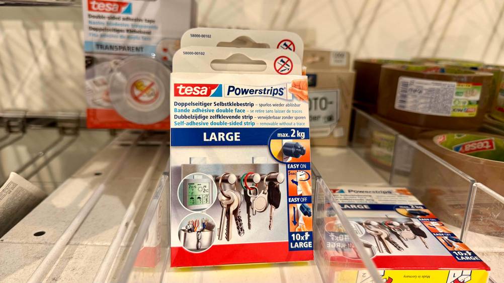 Mehrere Packungen der Tesa-Powerstrips im Test neben anderen Produkten in einem Verkaufsregal.