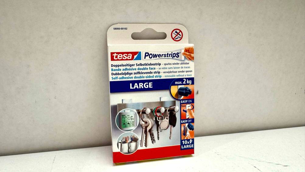 Eine Packung der getesteten Tesa-Powerstrips vor einer hellen Wand.