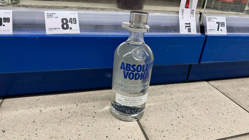 Eine Flasche mit getestetem Vodka Absolut steht vor einem Regal auf dem Boden.