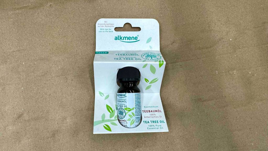 Eine Flasche mit hundertprozentig purem Alkmene Teebaumöl im Test liegt innerhalb der Verpackung auf dem Boden.