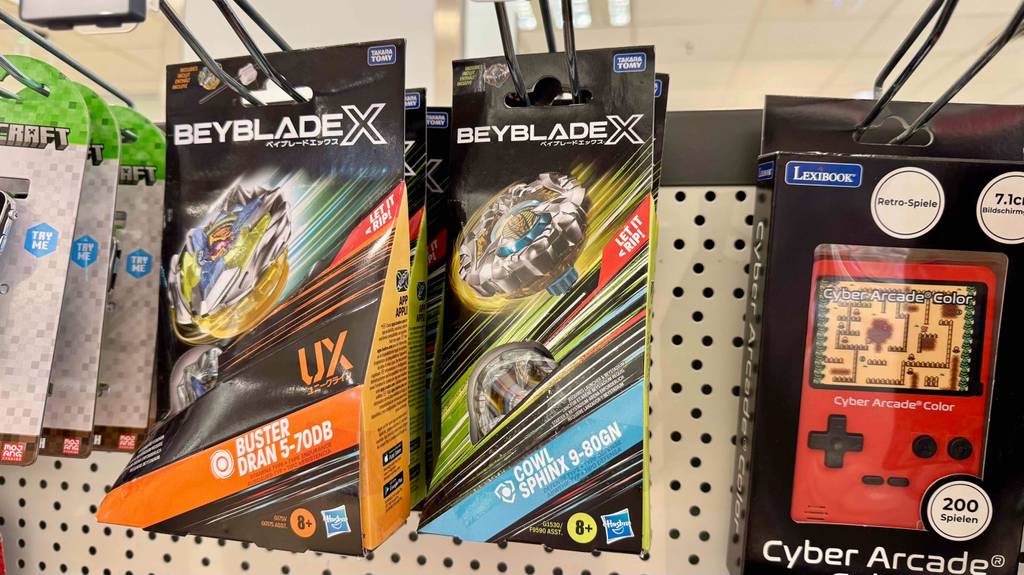 Getestet: Beyblade-Spielzeuge in Originalverpackungen hängen neben weiteren Spielzeugen an einem Verkaufsstand.