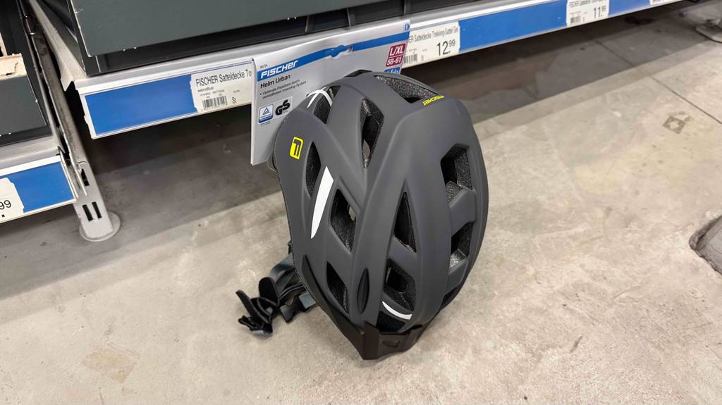 Test: Ein Fischer-Fahrradhelm in Dunkelgrau lehnt an einem Regal.
