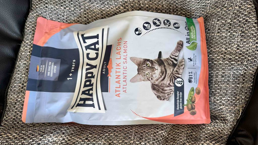 Eine wiederverschließbare Portionstüte mit Happy Cat Katzenfutter im Test liegt auf einem Kissen.