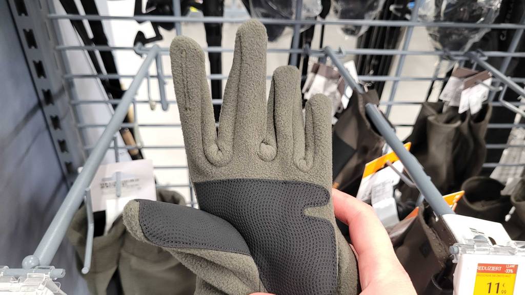 Jagdhandschuhe im Test: Ein grauer Jagdhandschuh vor einem Verkaufsregal.