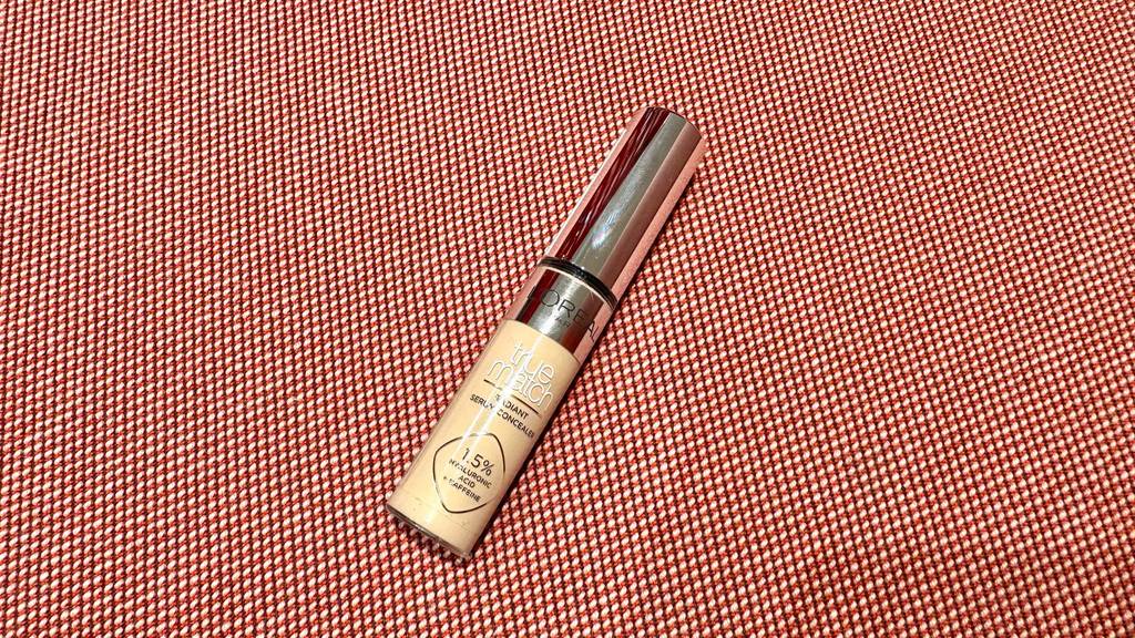 Ein getesteter L'Oréal-Concealer liegt auf einer roten Oberfläche.