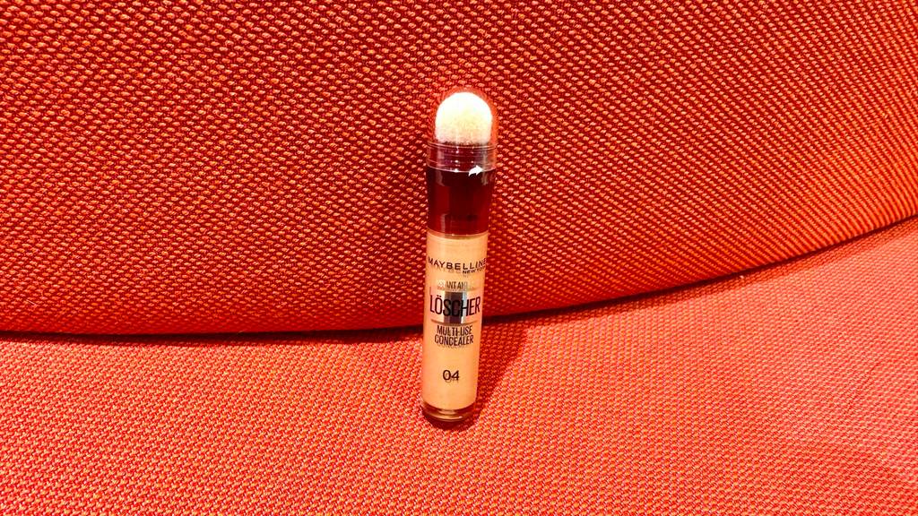 Ein Maybelline-Concealer im Test steht auf einem roten Hocker.