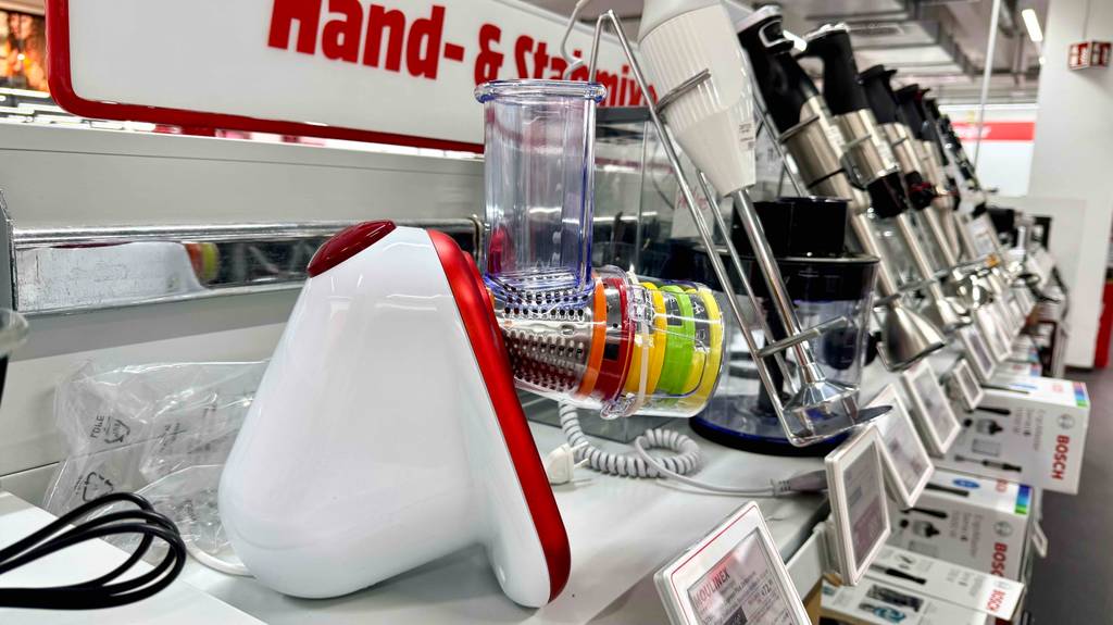 Ein weiß-bunter Moulinex-Zerkleinerer im Test steht auf einem Verkaufsregal neben weiteren Mixern.