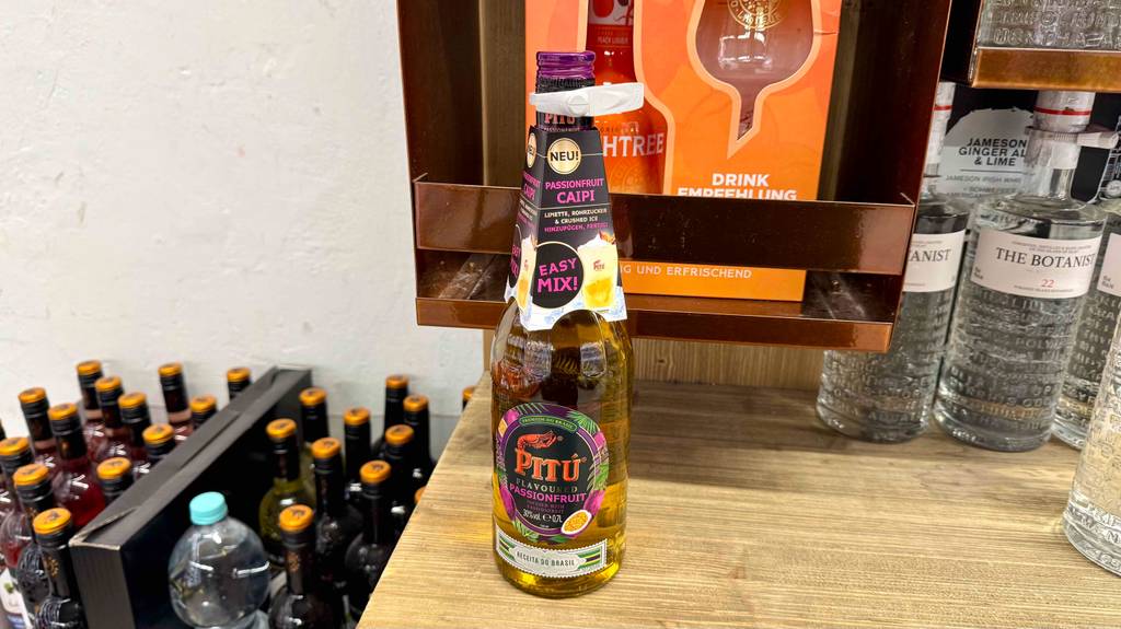 Ein getesteter Pitú-Schnaps in der Flasche mit Passionsfrucht-Geschmack steht auf einem Ausstellungsregal neben anderen Spirituosen.