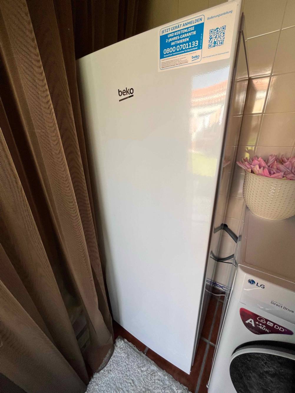 Mannshoher, weißer Beko-Kühlschrank im Test steht in einem Haushaltsraum.