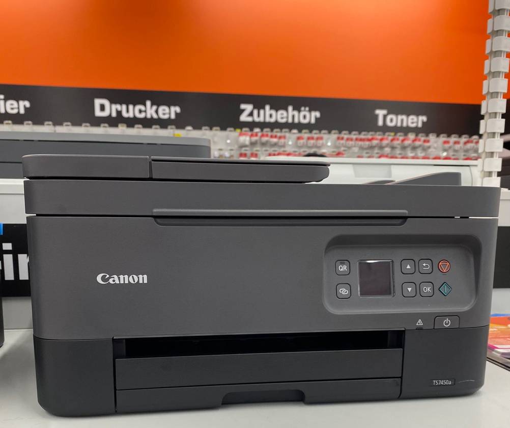 Ein schwarzer Canon-Drucker auf einem Tisch mit orangenem Hintergrund