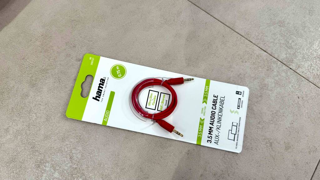 Ein getestetes Aux-Kabel in der Verpackung liegt auf einem Zementbelag.