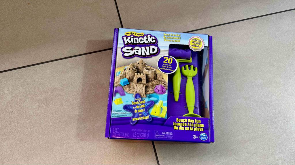 Getesteter Kinetic Sand in seiner Originalverpackung inklusive Zubehör liegt auf dem Boden.