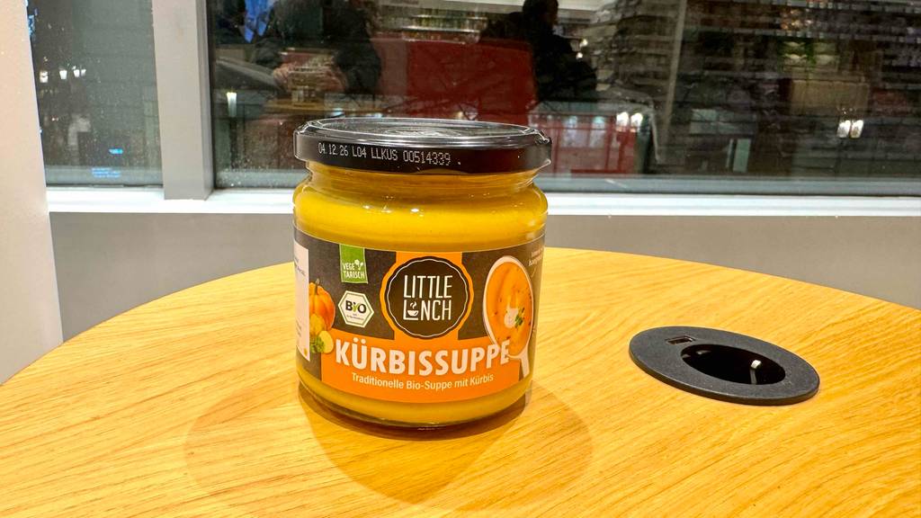 Eine getestete Little-Lunch-Kürbissuppe im Glas steht auf einem Holztisch.