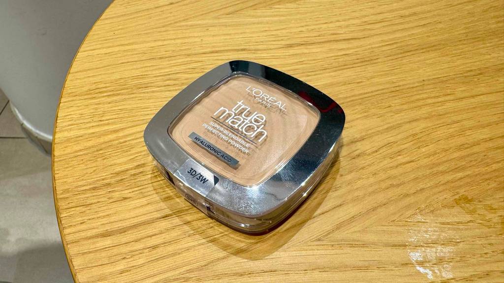 Eine Dose mit L'Oréal-Puder im Test liegt auf einem Holztisch.