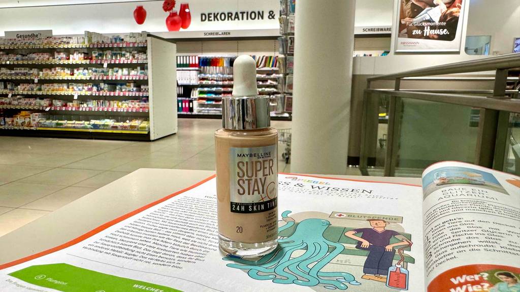 Maybelline-Make-Up im Test: Eine Flasche inklusive Pipette steht auf einem Buch im Drogeriemarkt.