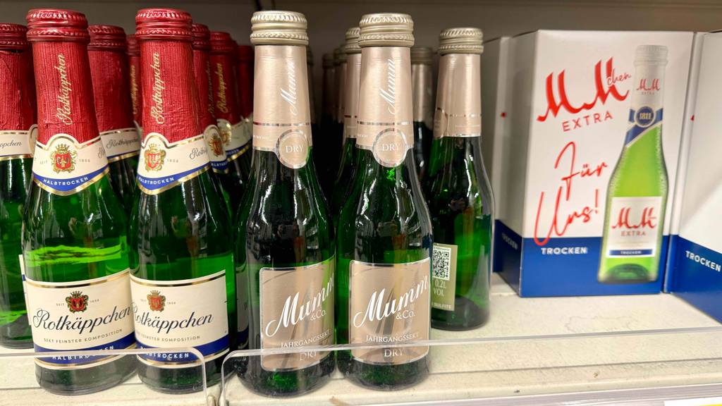 Mehrere Portionsflaschen mit Mumm Sekt im Test stehen nebeneinander auf einem Verkaufsregal.