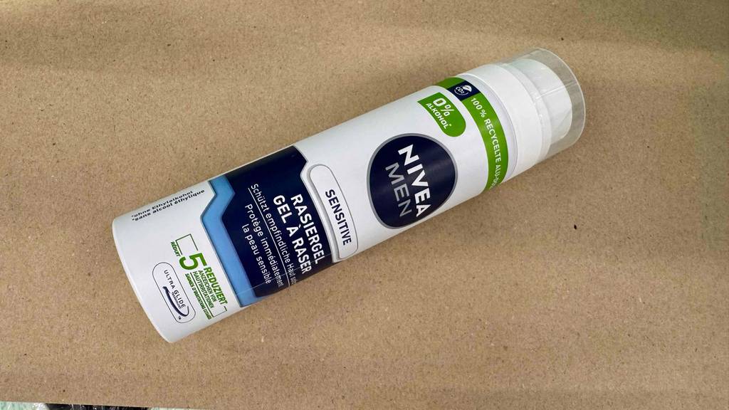 Eine recycelte Dose mit Nivea-Rasierschaum im Test liegt auf einer beigefarbenen Oberfläche.