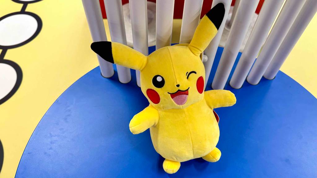 Ein gelbes getestetes Pokémon-Kuscheltier lehnt an einem weißen Tisch.