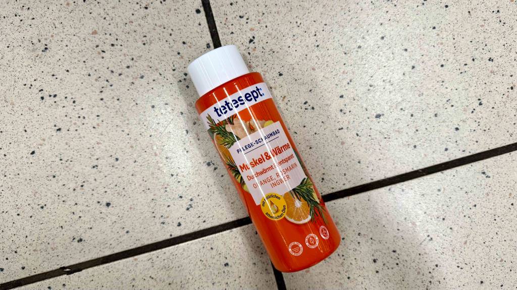 Eine Flasche getesteter Badezusatz liegt auf einem Fliesenboden.