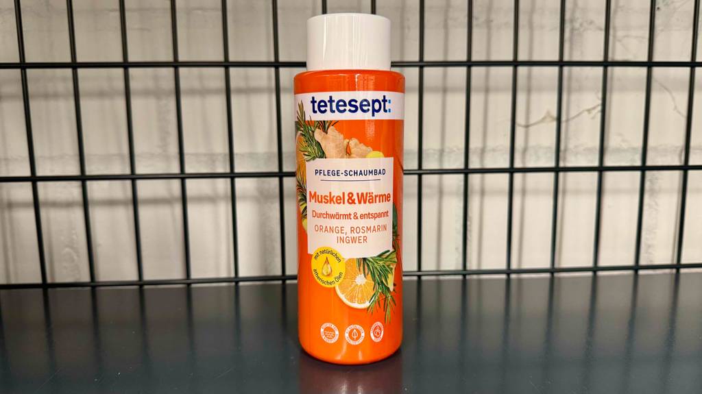 Eine Flasche Badezusatz steht zum testen in einem schwarzen Gitterregal.