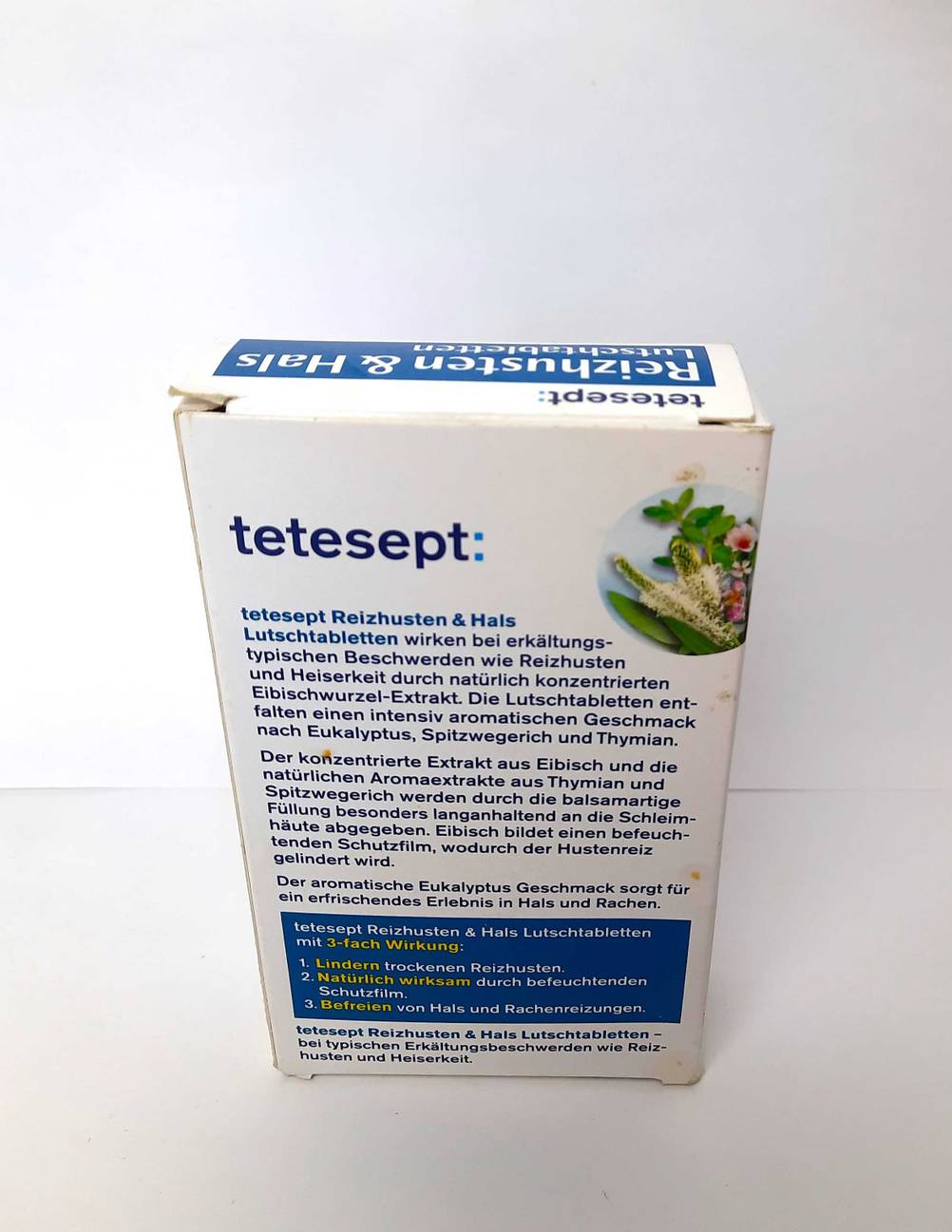Die Kartonverpackung von getestetem Mittel gegen Reizhusten steht mit der Rückseite nach vorn auf einer weißen Fläche.