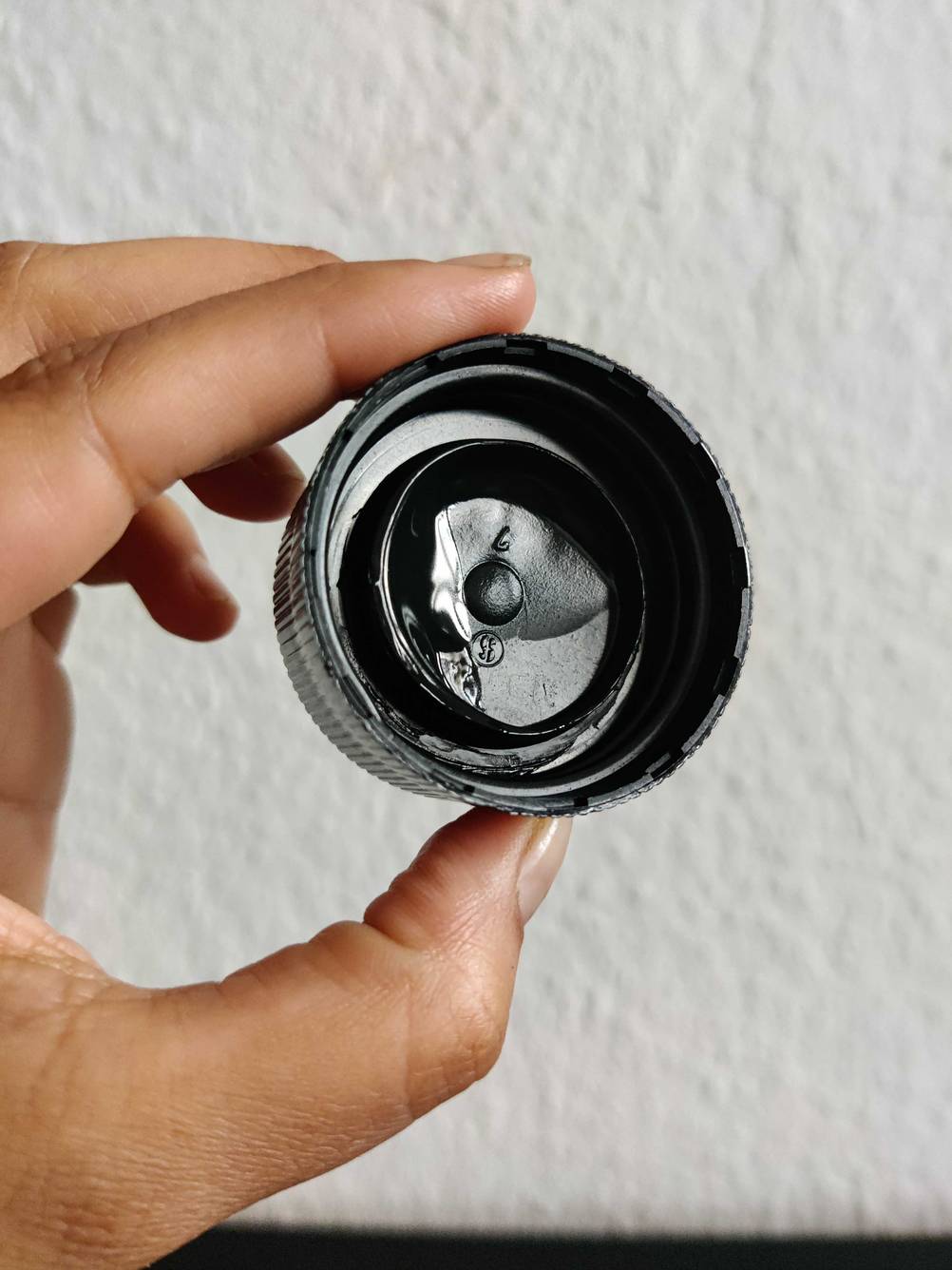 Eine Hand hält den Deckel der getesteten Textilfarbe mit Flüssigkeit darin.