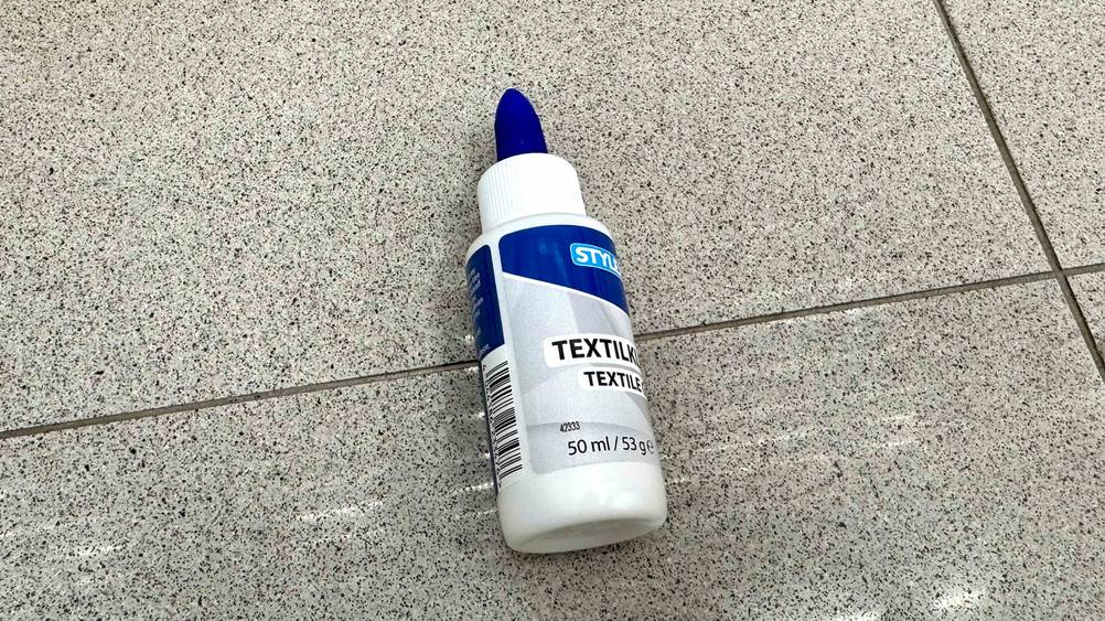 Auf einer Fließenfläche liegt ein getesteter Textilkleber.