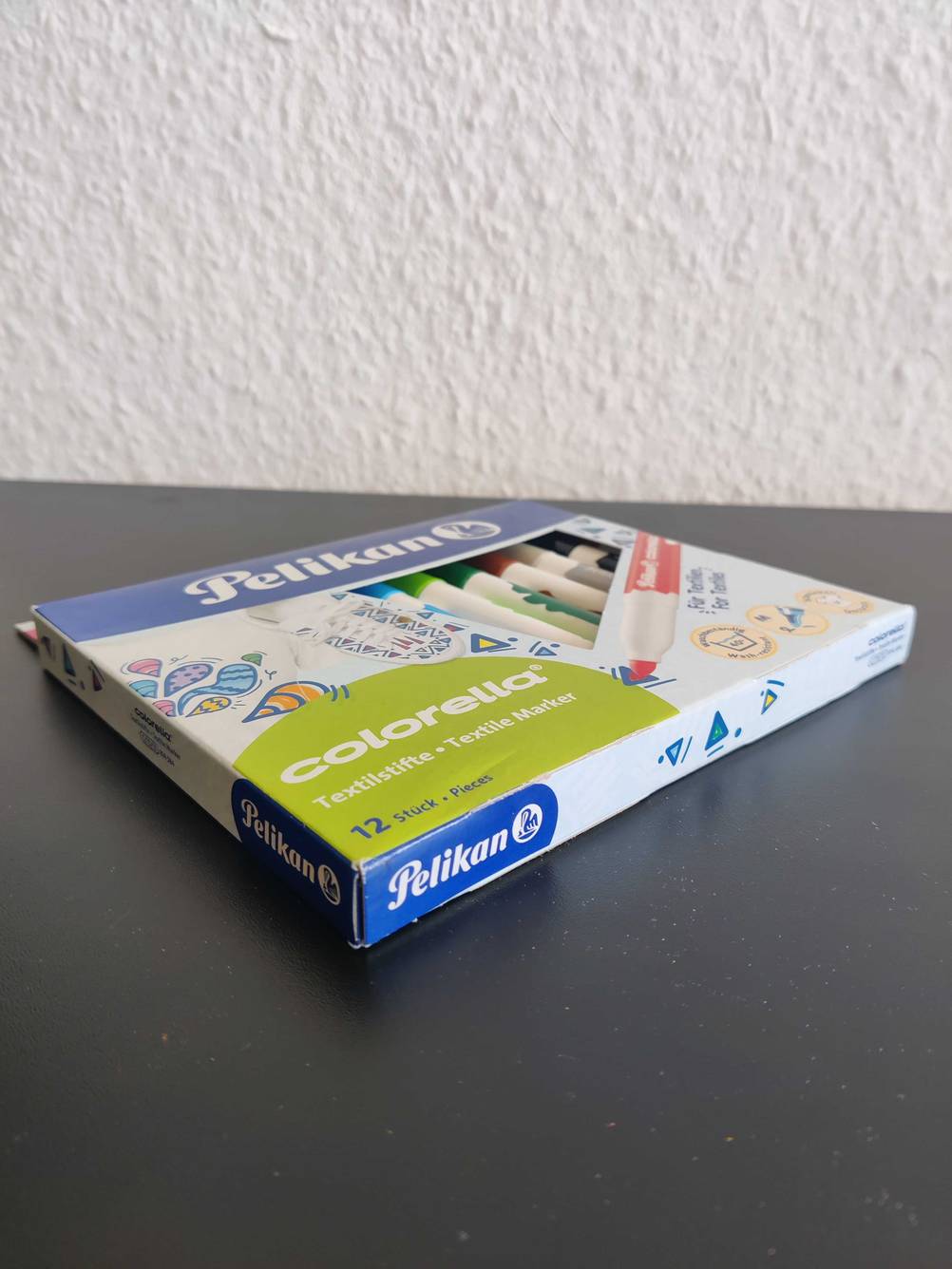 Verpackung gefüllt mit getesteten Textilstiften liegt auf einem Tisch. 