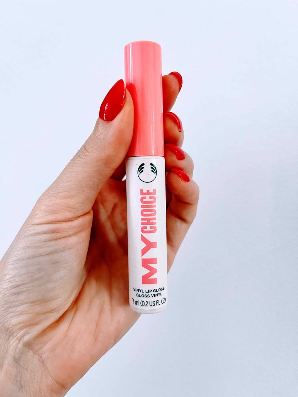 Im Test: Hand hält ein Fläschchen Lip Plumer My Choice vor weißer Wand.