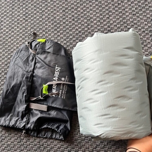 Die Therm-A-Rest Trail Lite liegt neben ihrer Schutzhülle auf einem Teppich