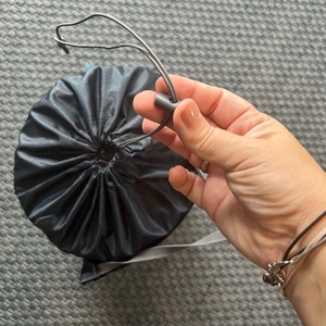 Eine Hand hält den Gummizug an der Schutzhülle der Therm-A-Rest Trail Lite fest