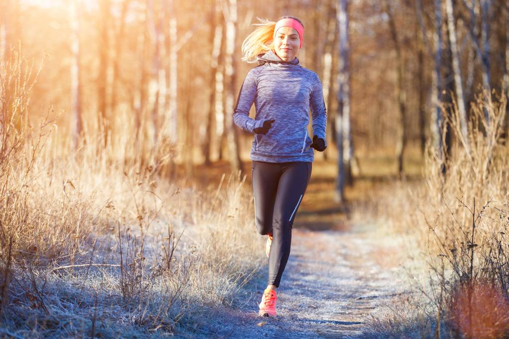 Thermo-Laufhose für Damen im Test: Eine Frau ist in Funktions-Laufkleidung gekleidet und läuft in einer winterlichen Landschaft. 