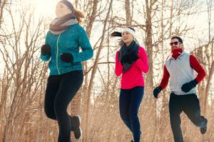 Thermo-Laufhose-Damen-Test: Zwei Frauen und ein Mann sind in Winter-Laufkleidung gekleidet und laufen im Wald. 
