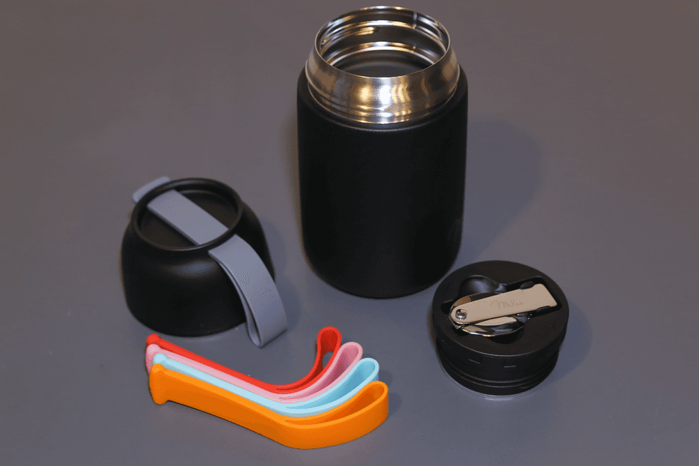 Thermo-Lunchboxen getestet: Neben der Thermo-Lunchbox von Milu liegen verschiedenfarbige Trageschlaufen.