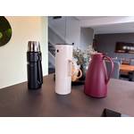 Drei Thermokannen stehen nebeneinander auf einer Küchenarbeitsplatte vor einem Tablet mit Blumen