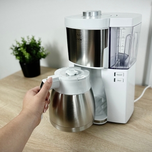 Eine Hand setzt die Thermoskanne der Melitta Look V Perfection in die Maschine ein. Die Öffnung zeigt nach oben.