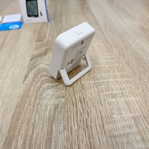 Ein Govee-H5075001DE-Thermometer steht seitlich aufgestellt auf einem Tisch und zeigt die Gehäuseform.